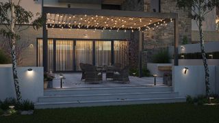 patio at night with garden lights on the steps and walls and festoon lights on a pergola overhead