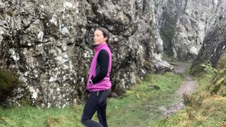 Woman hiking amongst rocks wearing purple vest