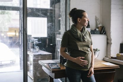 Woman with fibroids when pregnant looking out of the window in an office