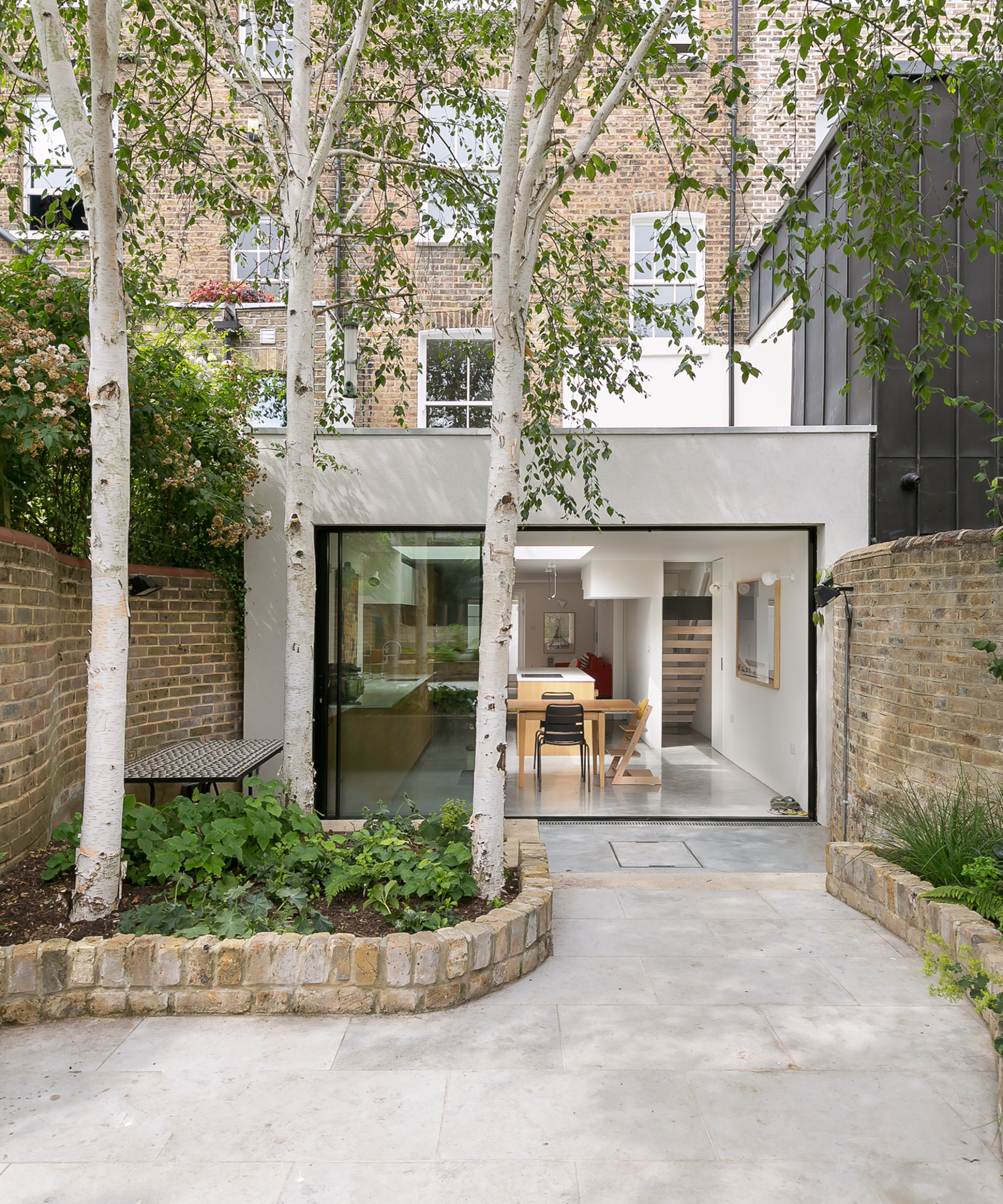 exterior view of small house extension with white rendered exterior and large glass bi-fold patio doors
