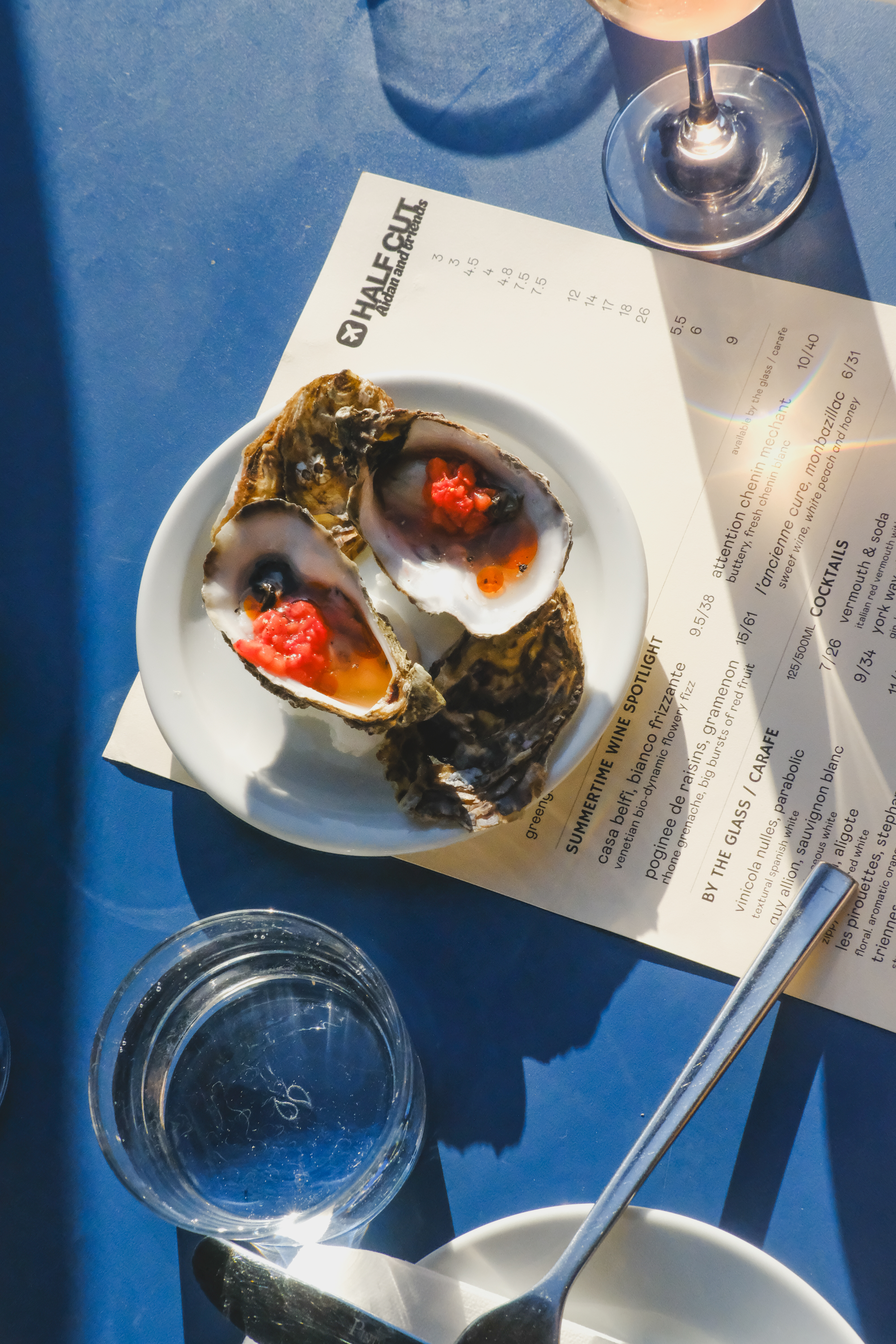 an image of an oyster dish on a menu on an outdoor table at Half Cut Market on a sunny day