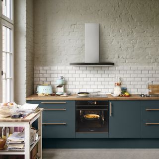 Modern kitchen ideas by Smeg, with sea green cabinetry, brass handles and a painted brick wall.