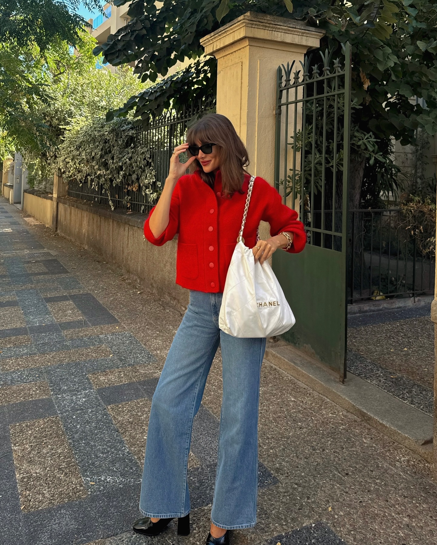 Julie wears a red cardigan, blue flared jeans and platform shoes