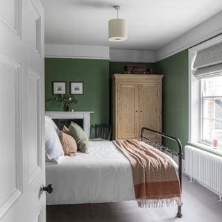 Green bedroom with wrought iron bed