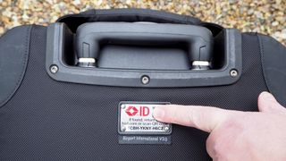 Finger pointing to the logo on a Think Tank Airport International V3.0 travel case