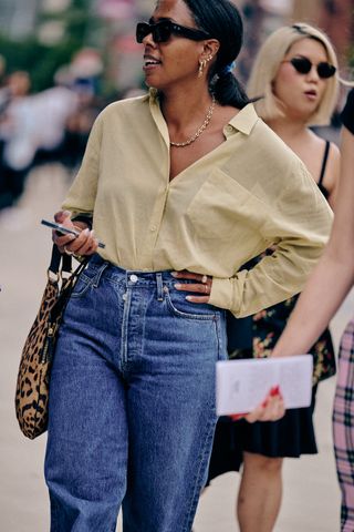 A NYFW SS25 Street Style guest wearing a yellow button-down shirt and blue jeans and a cheetah print bag