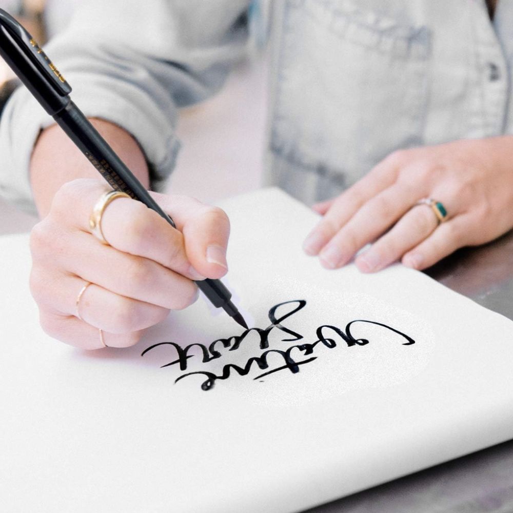 Close up of woman's hand writing in calligraphy script on a white pad