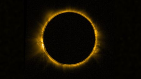 detailed view of the sun blocked by the moon in the center, creating a dramatic ring of fire against a black background. The sun's corona is visible around the edge of the moon.