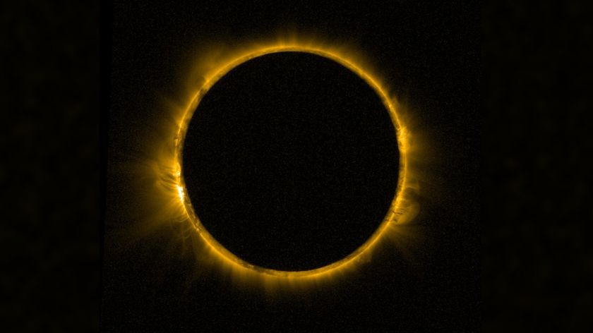 detailed view of the sun blocked by the moon in the center, creating a dramatic ring of fire against a black background. The sun's corona is visible around the edge of the moon. 