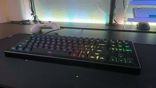 The Drop CSTM80 mechanical keyboard on a black desk with rainbow RGB backlighting visible