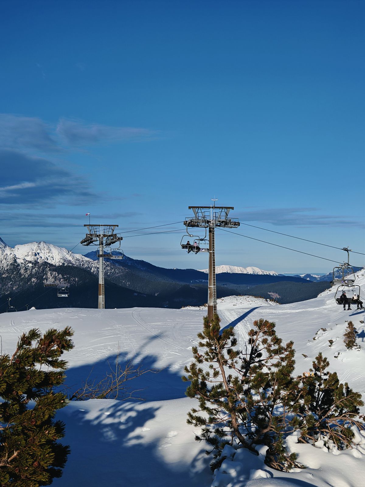 A series of ski lifts going across snowy mountains
