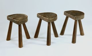 Three three-legged wood stools with half circle tops.