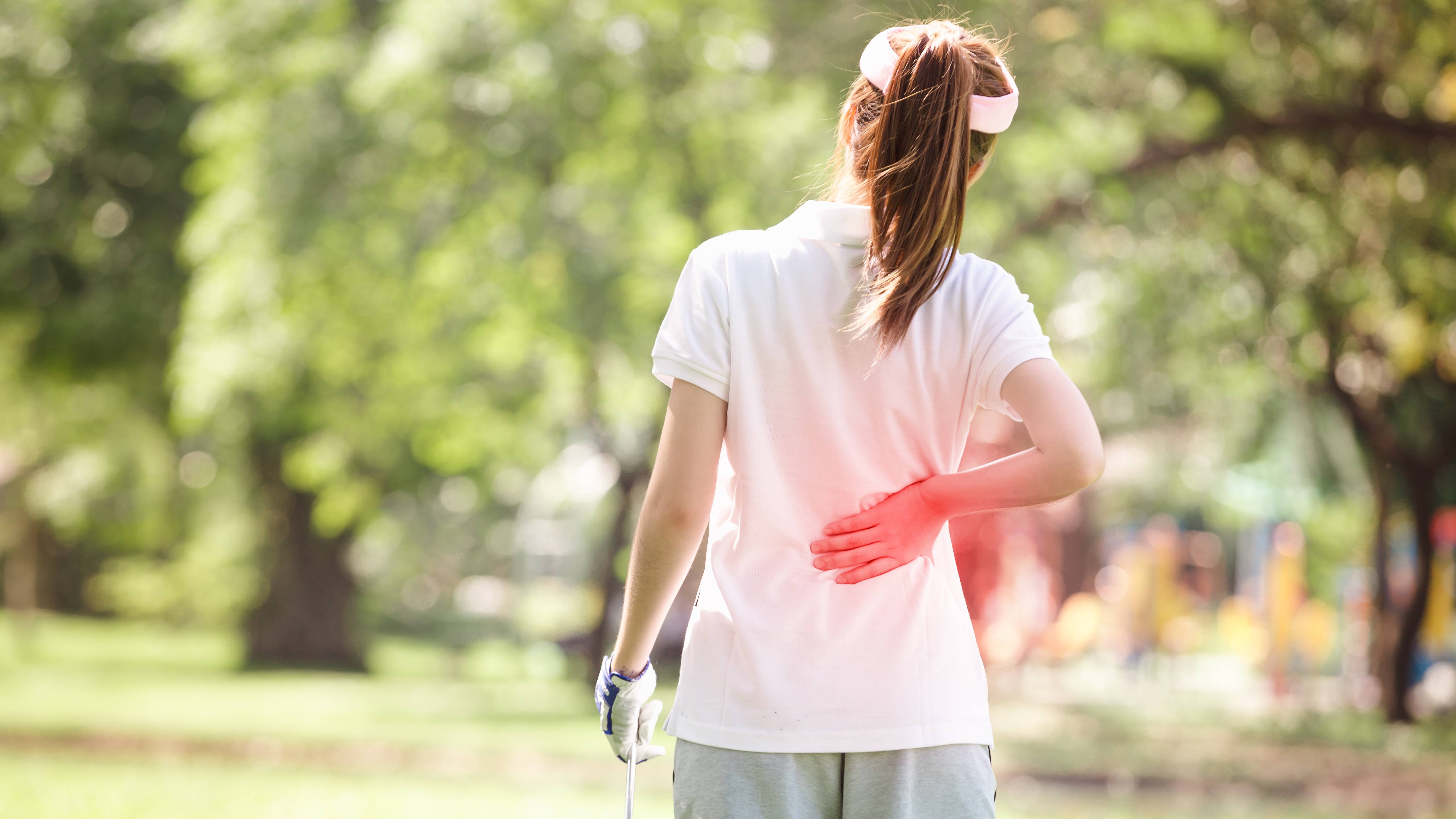 Female golfer holding her injured back