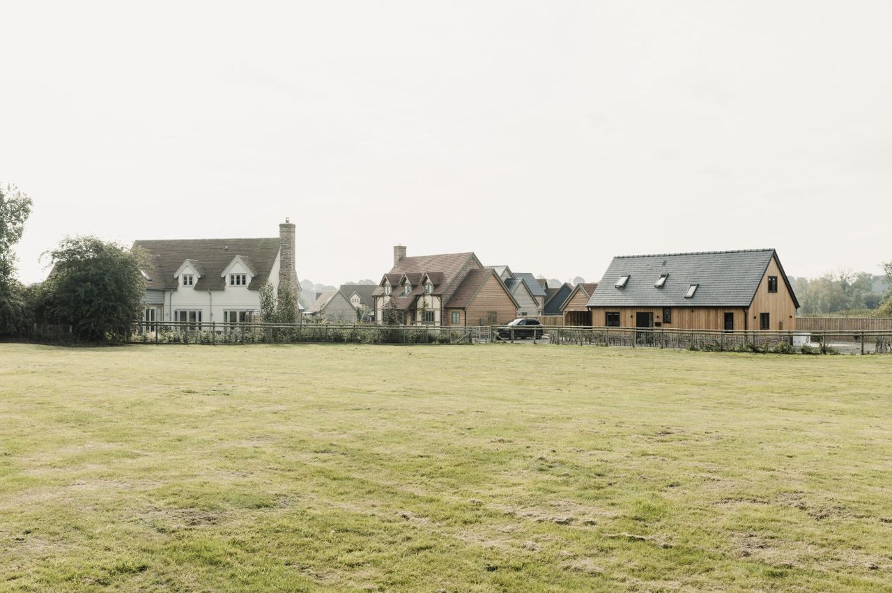 Three oak frame houses in a row with a green field in front of them