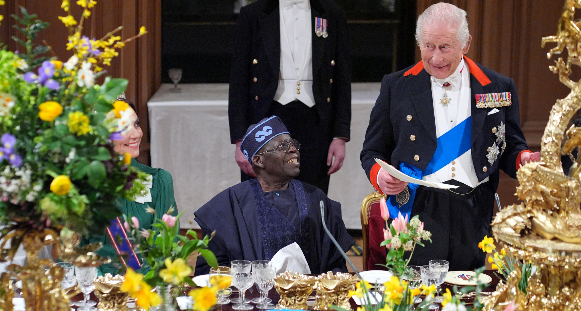 King Charles reading from a paper at a banquet table