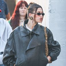 Hailey Bieber wearing a leather jacket and leopard-print bag