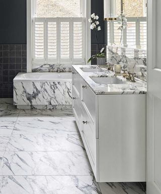marble bathroom with tub and cabinetry