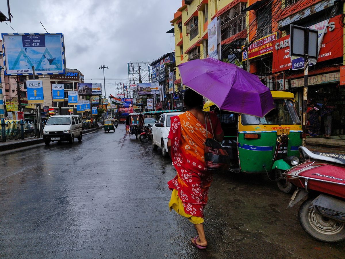 A woman holds an umbrella while walking on the street during rain due to Cyclone Dana in Kolkata, India