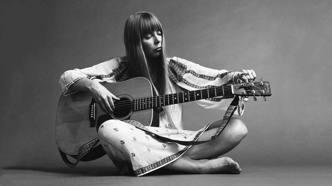 Joni Mitchell tuning an acoustic guitar (studio portrait)
