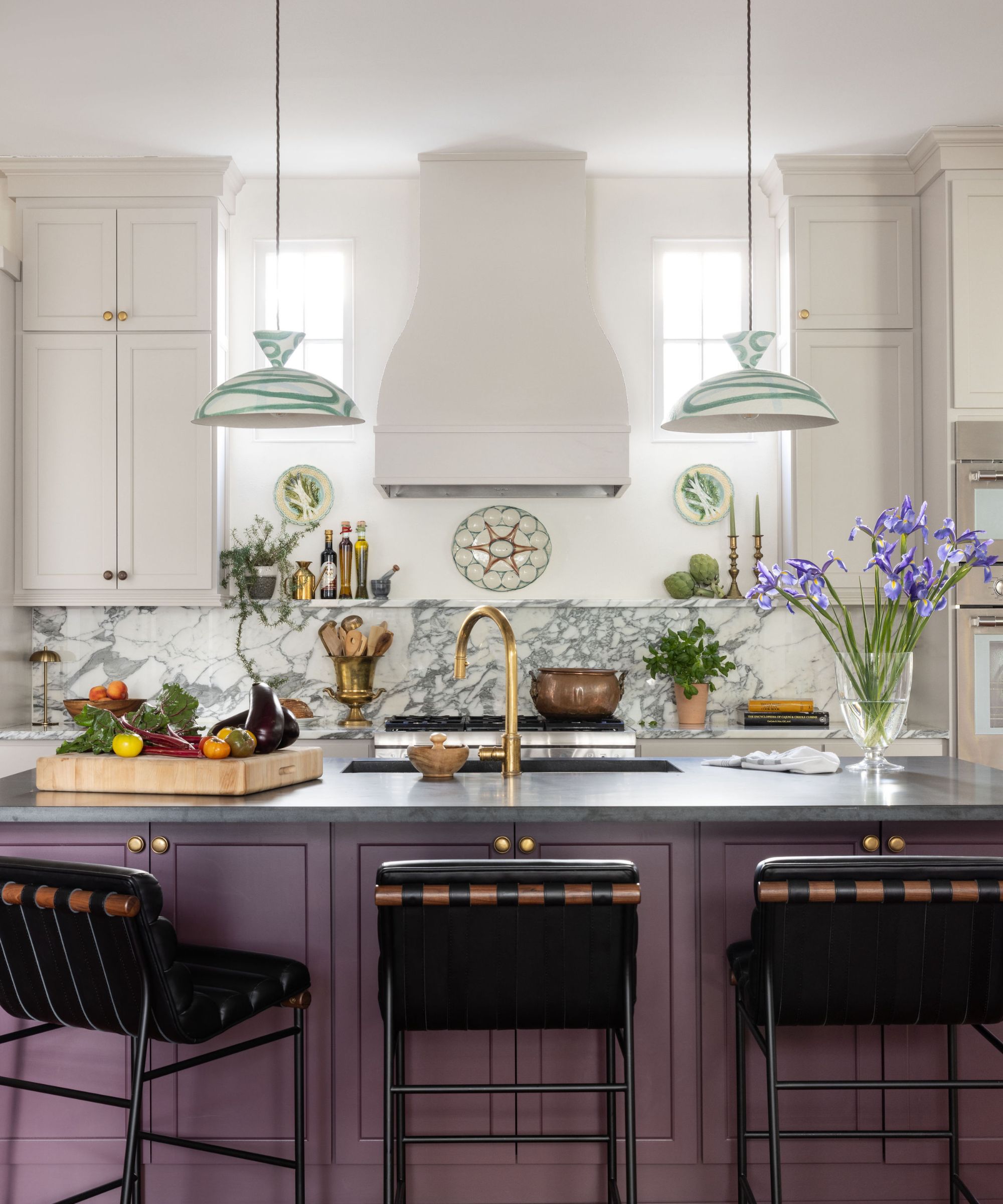 A kitchen with white cabinets, a purple island, and marble countertops