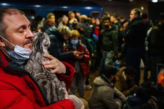 Caman Denysenko tries to calm his spooked cat as he joins hundreds of people seeking shelter underground, on the platform, inside the dark train cars, and even in the emergency exits, in metro subway station as the Russian invasion of Ukraine continues, in Kharkiv, Ukraine, Thursday, Feb. 24, 2022.