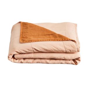 A folded blush pink and terracotta orange reversible quilt