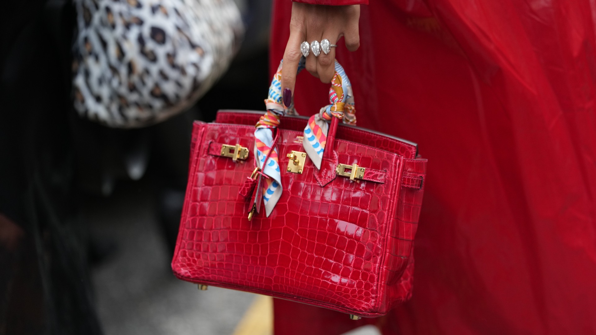 woman holding red birkin with cherry manicure