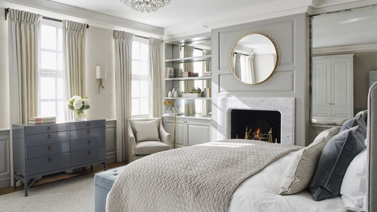 Grey bedroom ideas with pale grey wall panels and large mirror over a marble fireplace
