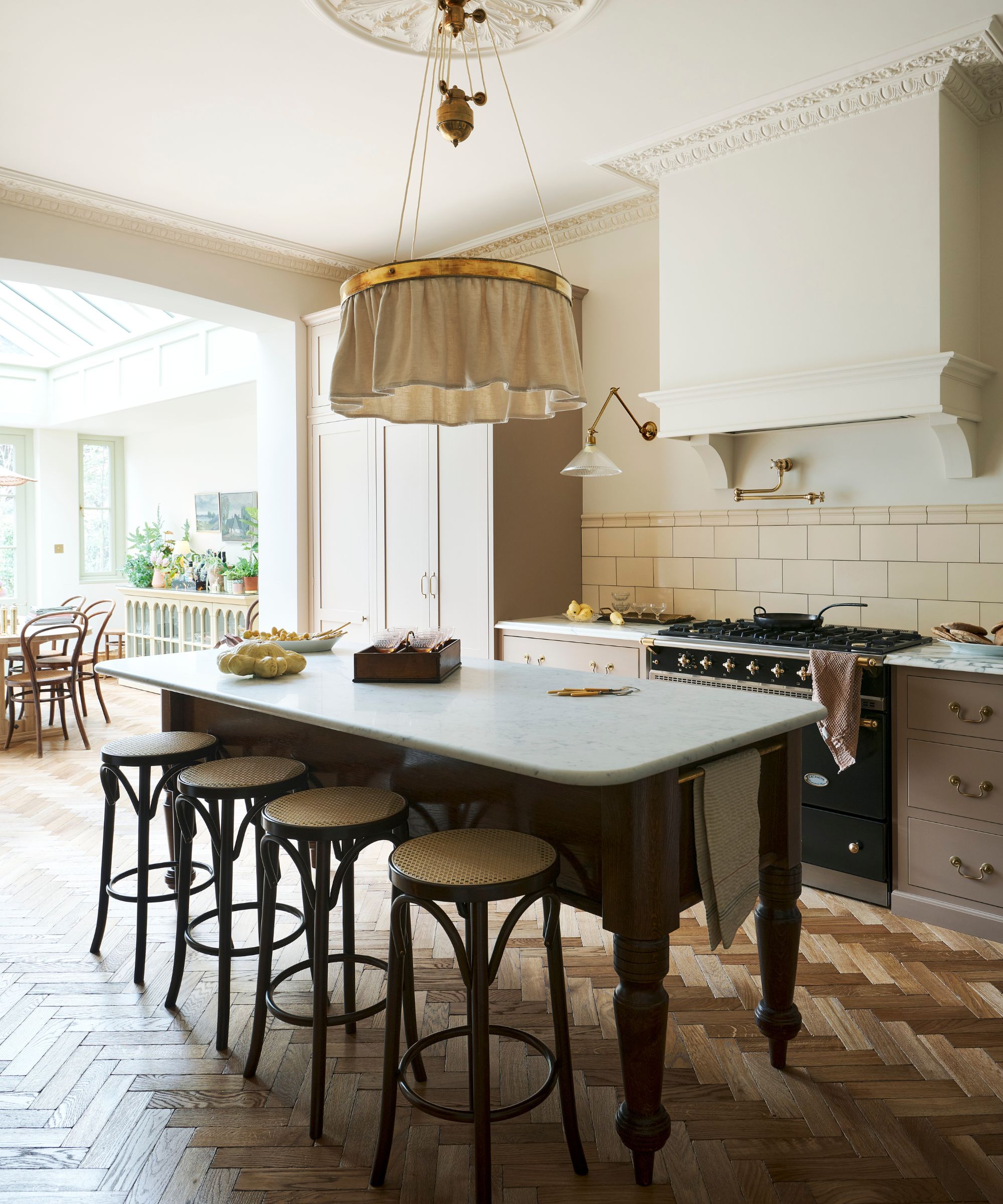 A kitchen with pink cabinets, cream walls, marble countertops, and a freestanding wooden island