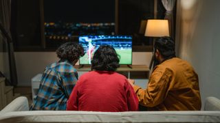Group of excited football fans cheering and celebrating in front of the TV 