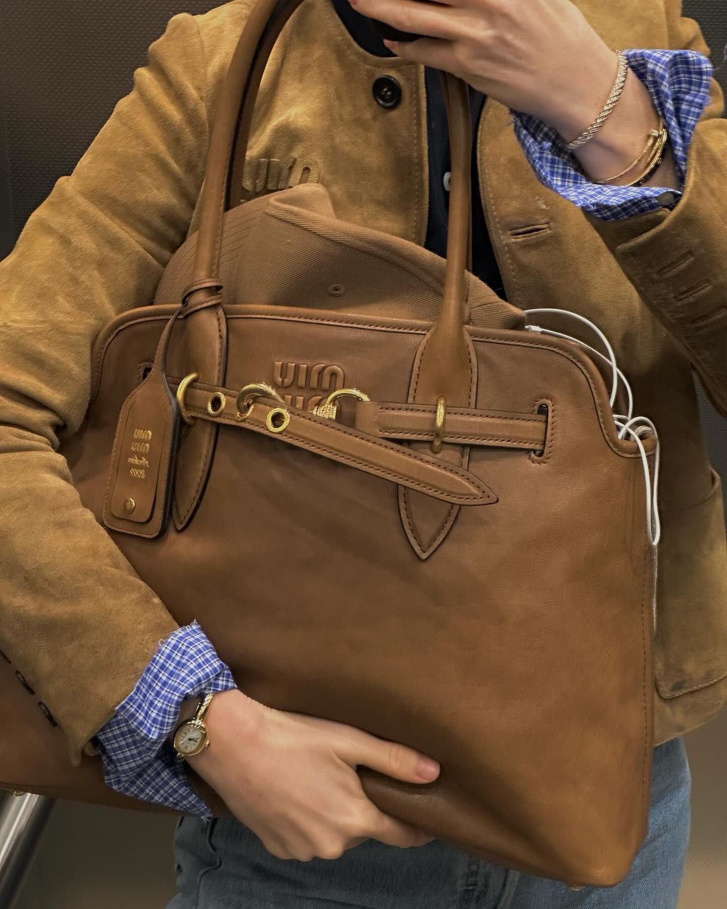 detail image of a woman holding a Miu Miu Aventure Bag in brown