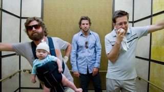Zach Galifianakis with a baby carrier, Bradley Cooper and Ed Helms in an elevator in The Hangover