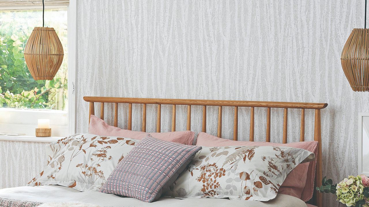 A bedroom with an organic-pattern wallpaper and a wooden bed with pendant lights on either side