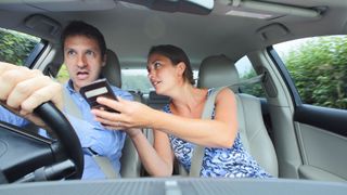 Paar im Auto schaut auf ein Telefon, um den Weg herauszufinden