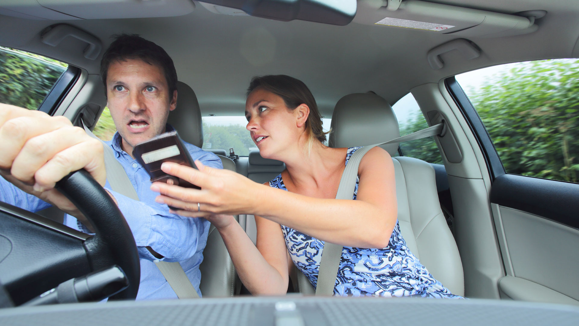 Paar im Auto schaut auf ein Telefon, um den Weg herauszufinden