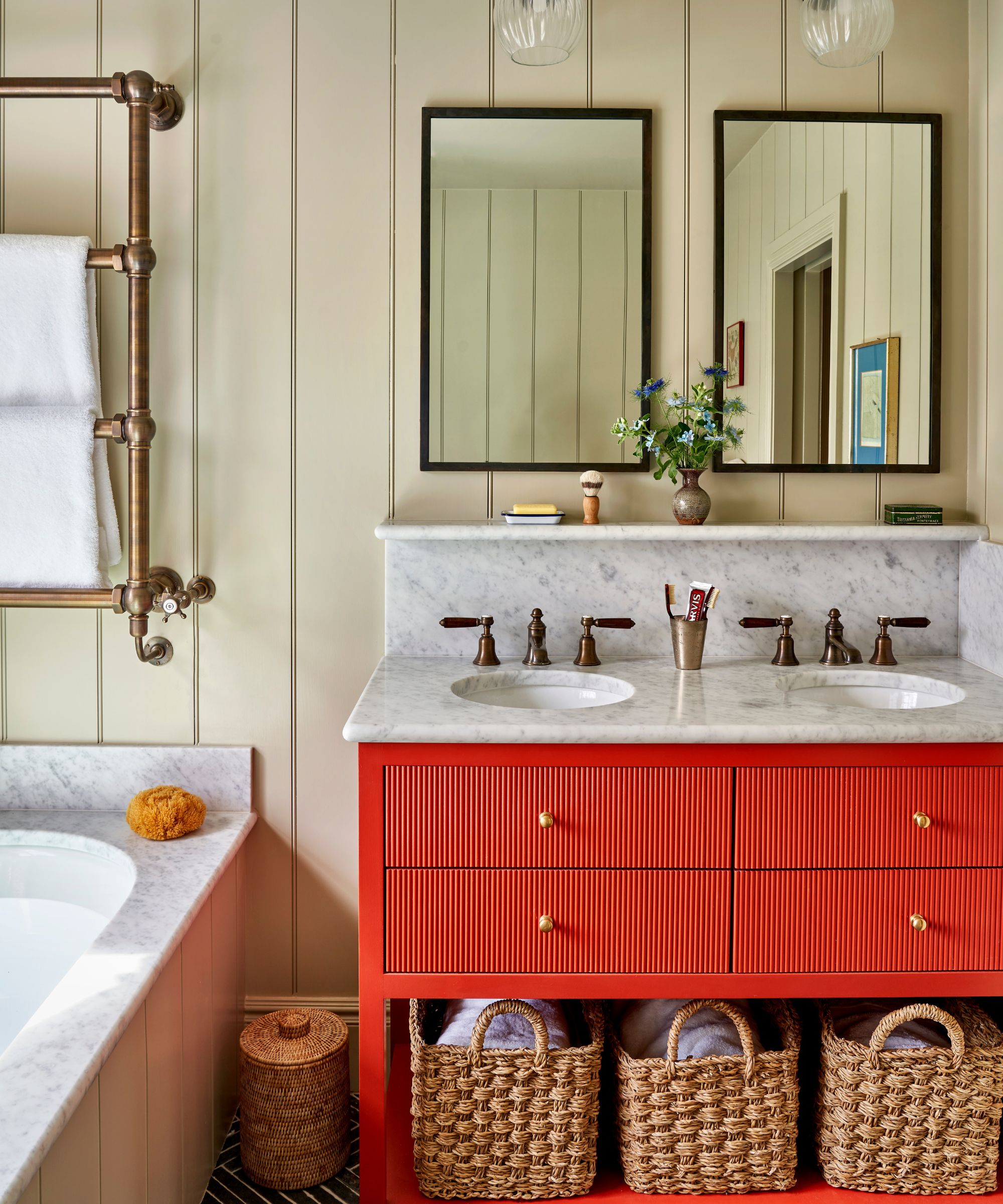 Paneled bathroom with red vanity and two black framed mirrors hanging above the sink