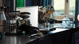 A black Faemina coffee maker on a smart countertop with a grinder at the side