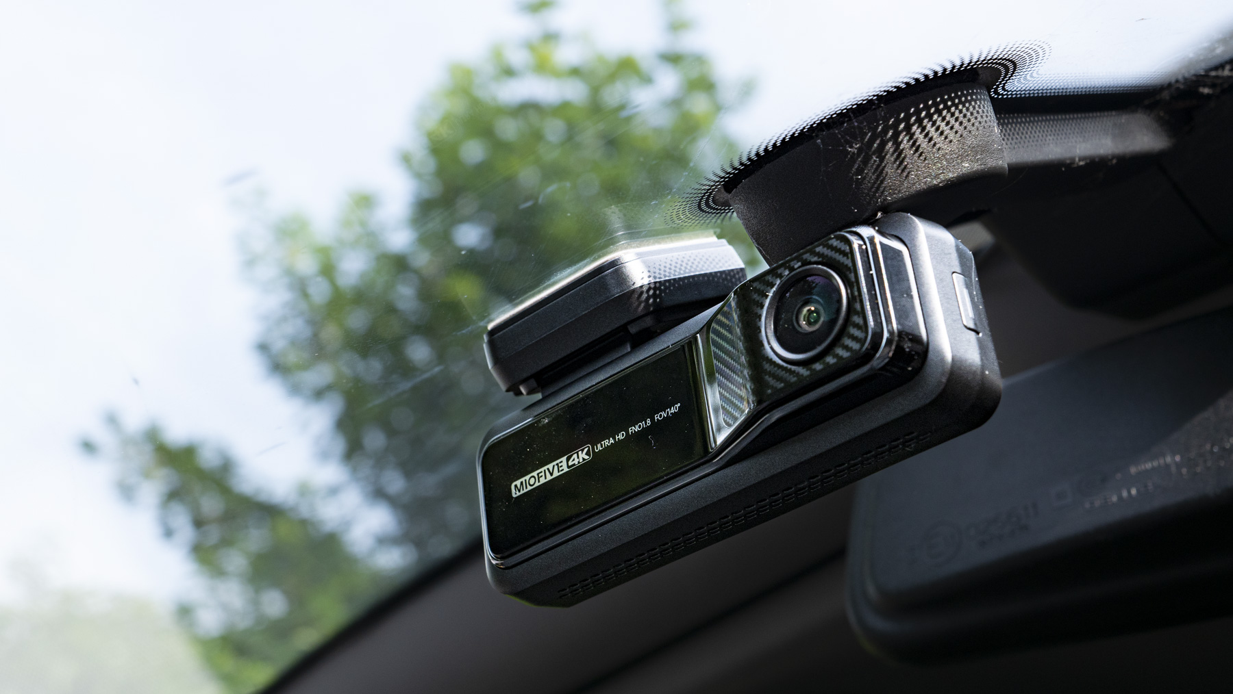 Miofive Dual Dash Cam front camera attached to a windscreen seen from low angle