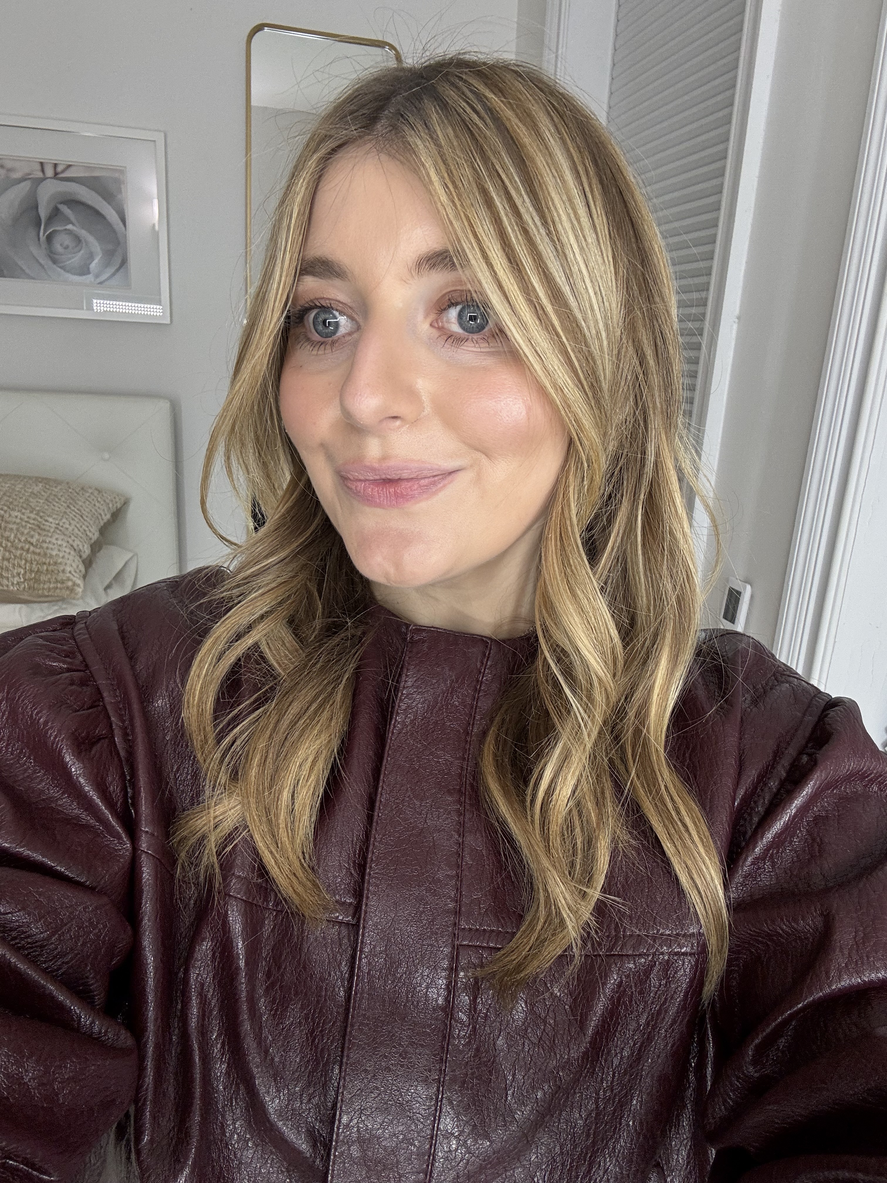 samantha holender in a maroon leather jacker with blonde hair and glowing skin