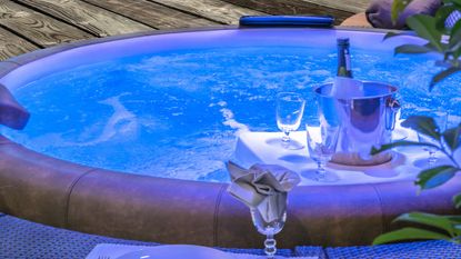 hot tub at night with lighting and a champagne bottle and glasses on a hot tub bar