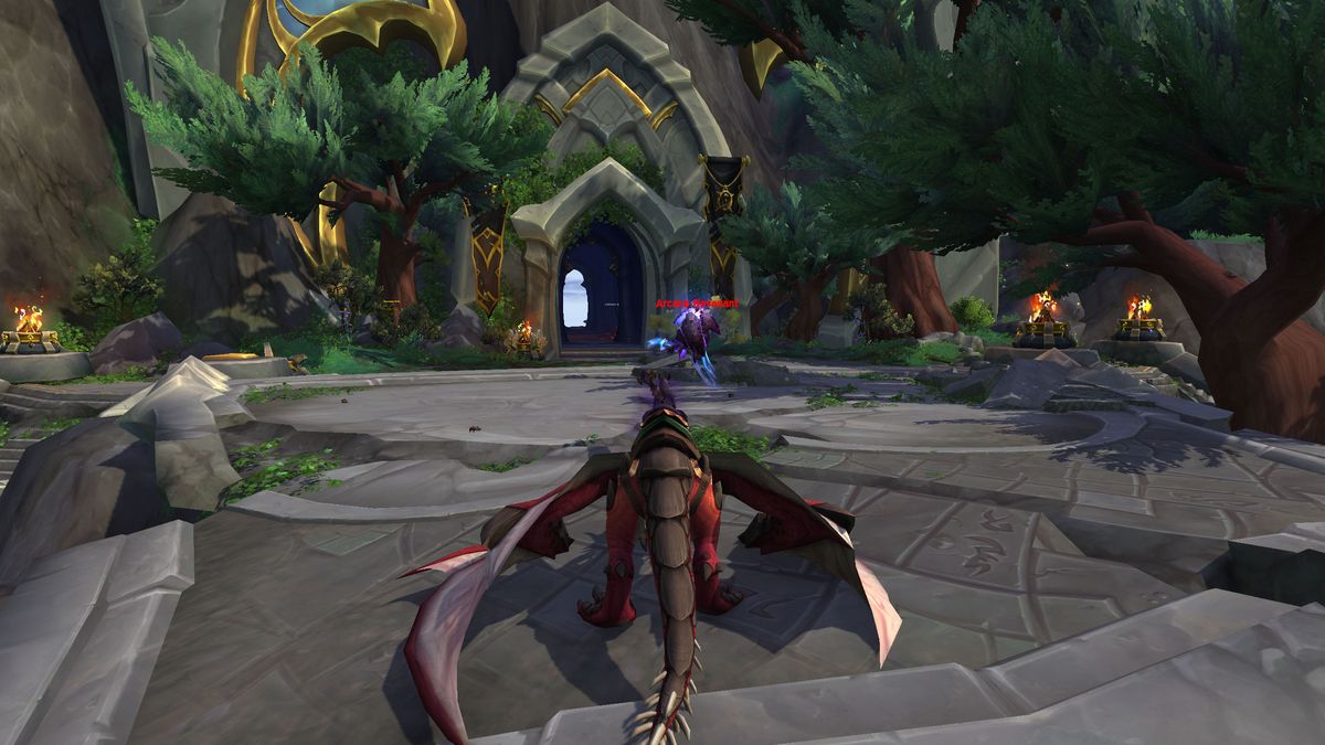 WoW Warden Entrix location - a character is sat on a dragonriding mount looking towards the doorway to a cave that holds Warden Entrix