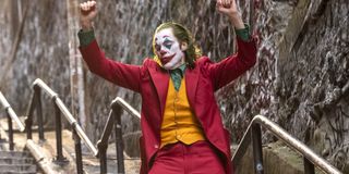 Joaquin Phoenix in makeup Joker arms raised on stairs