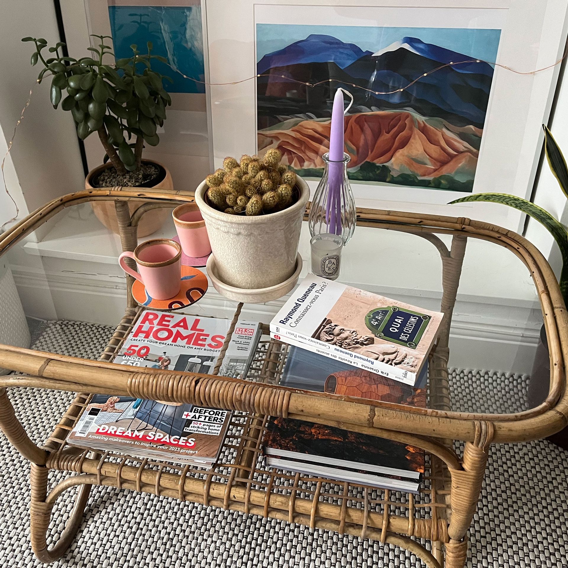 Meja kopi bergaya di area lounge putih dengan pembatas tanaman hias