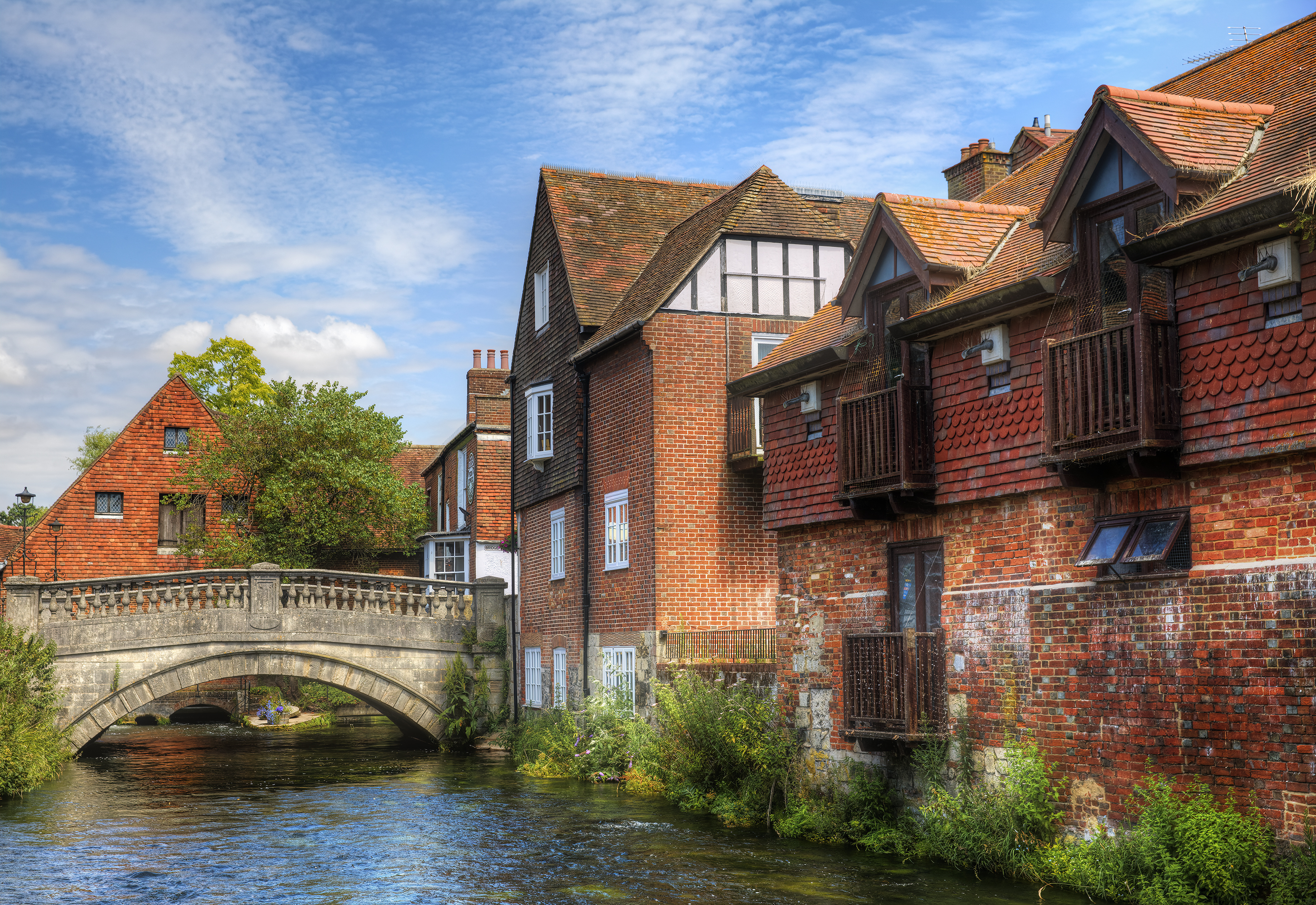 The First City Bridge, called the Soke Bridge, crossing the River Itchen in Winchester, England, built by St Swithun. It's an idyllic scene, with lots of red brick buildings