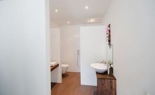 White bathroom/toilet with dark wood surface designs.