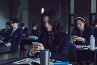 jung Jae-i (Roh Jeong-eui) looks at her phone as she sits in a full classroom, in Netflix k-drama 'Hierarchy'