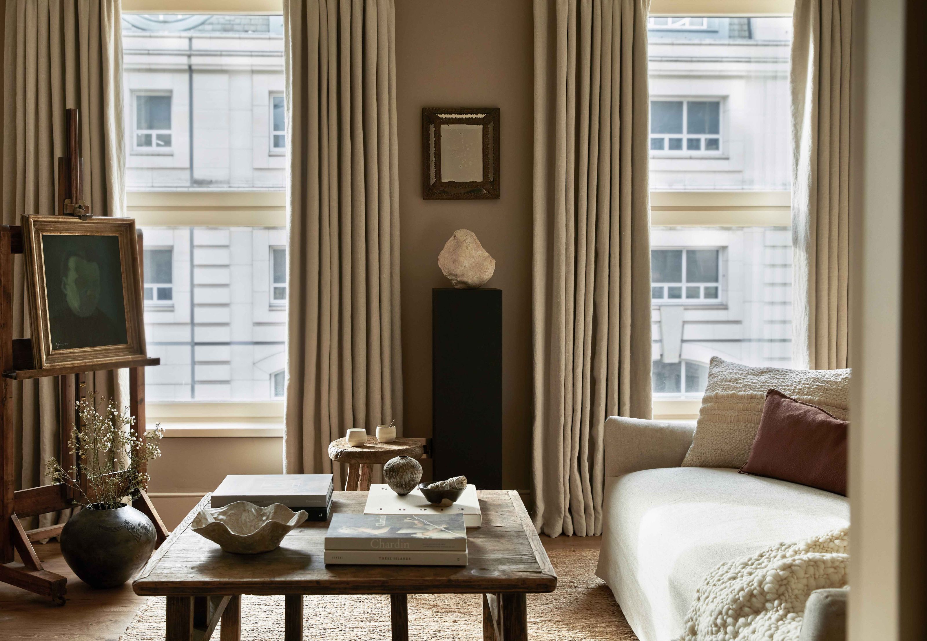 A contemporary living room with a painting on an easel and a sculpture displayed on a plinth