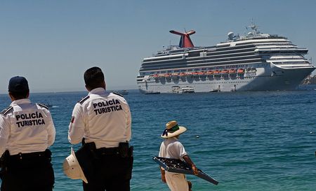 Police and a vendor stand on Medano Beach May 15, 2012 as the Carnival Cruise ship Splendor is anchored offshore in Los Cabos, Baja California, Mexico. 
