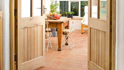 limed wood doors opening to a garden room with a wooden dining set, to illustrate how to lime wood