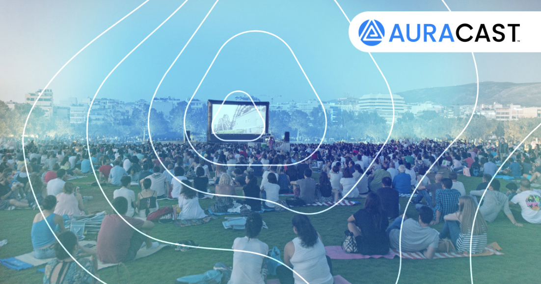 Bluetooth Auracast being used at a music festival, on a big screen with people watching and listening